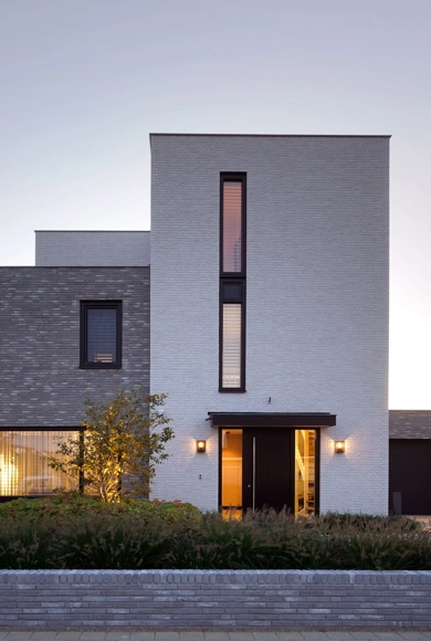 De voorgevel van een moderne, kubistische villa met wit en grijze gevelafwerking