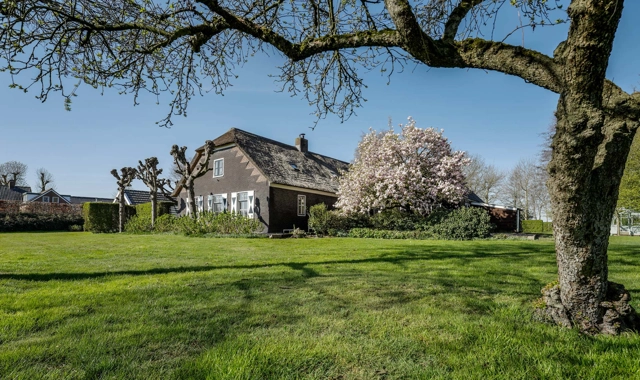 Landelijke boerderijwoning met donkere gevel op een groot perceel